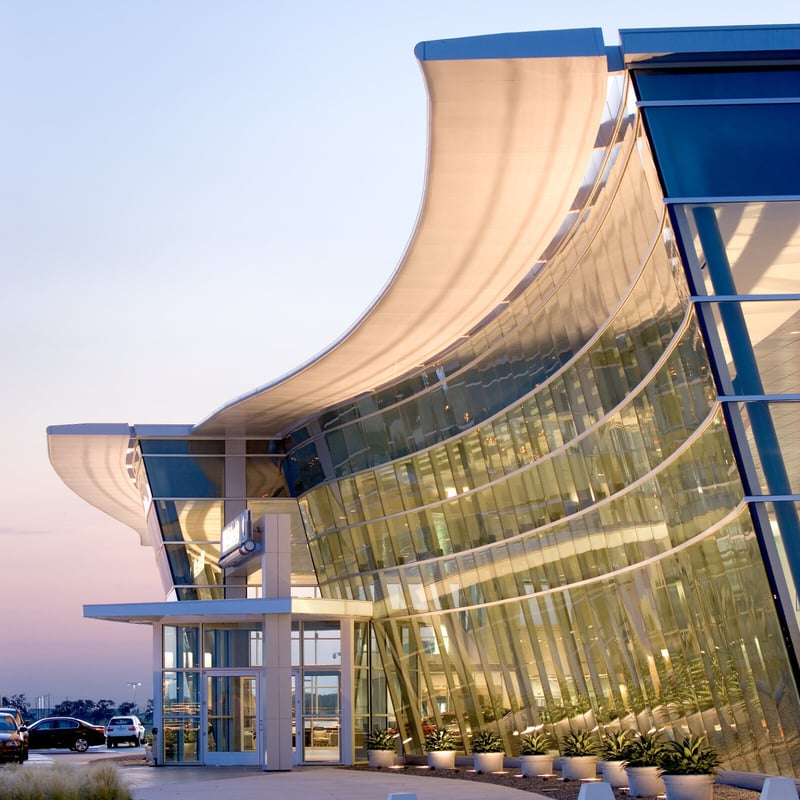 A contemporary building featuring a sleek, curved glass facade that reflects its modern architectural design