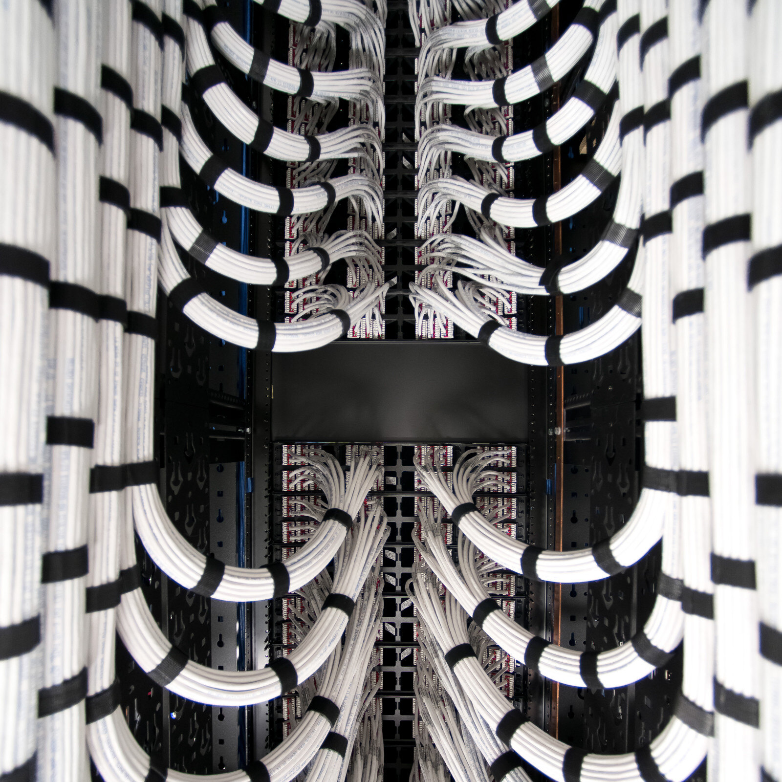 A large rack filled with numerous cables organized neatly in a modern data center environment