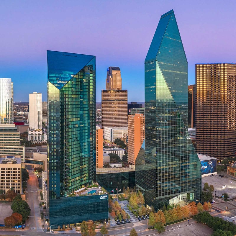 A skyline view of Dallas, Texas, showcasing modern buildings against a clear blue sky.