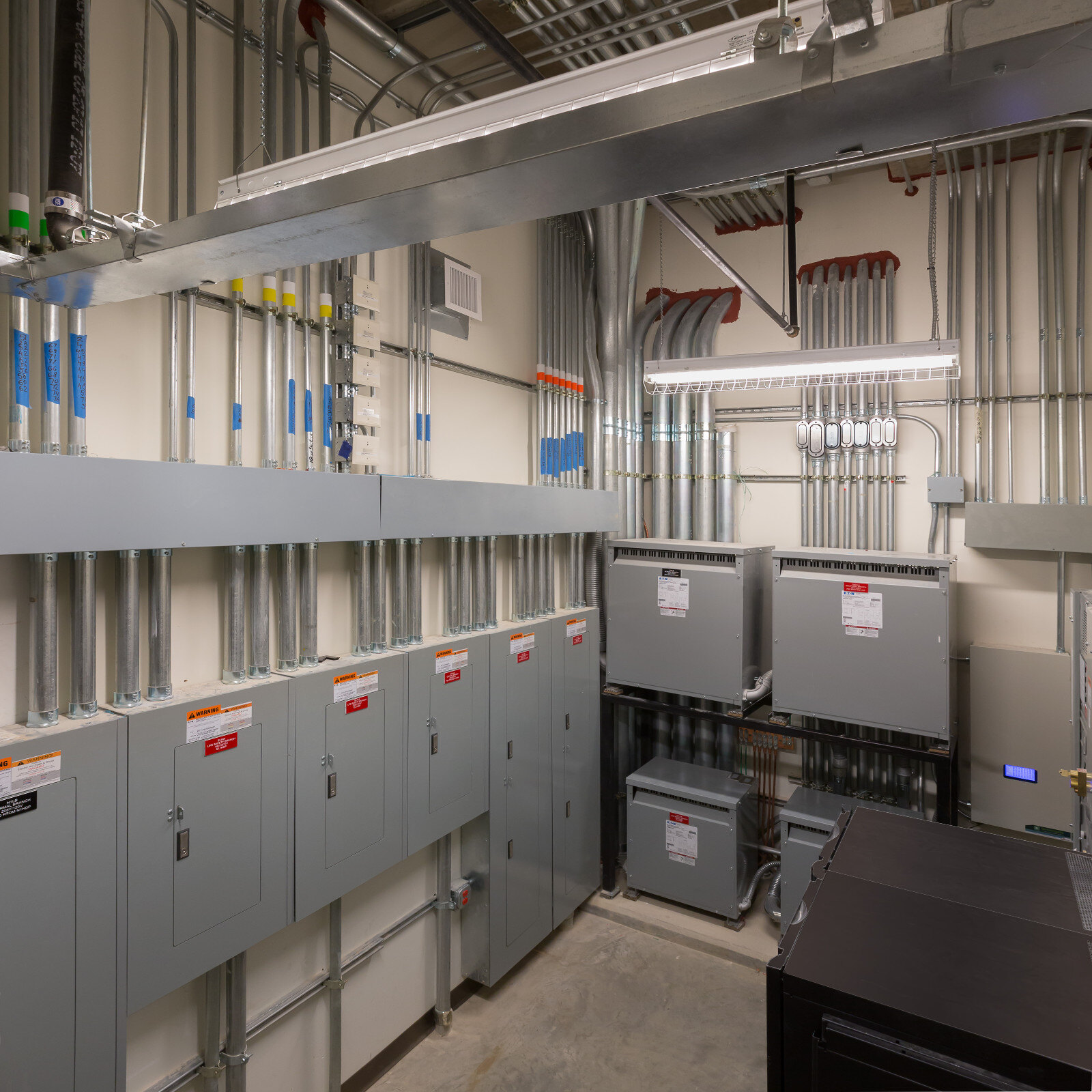 A spacious room filled with various electrical equipment and tangled wires, showcasing a technical environment