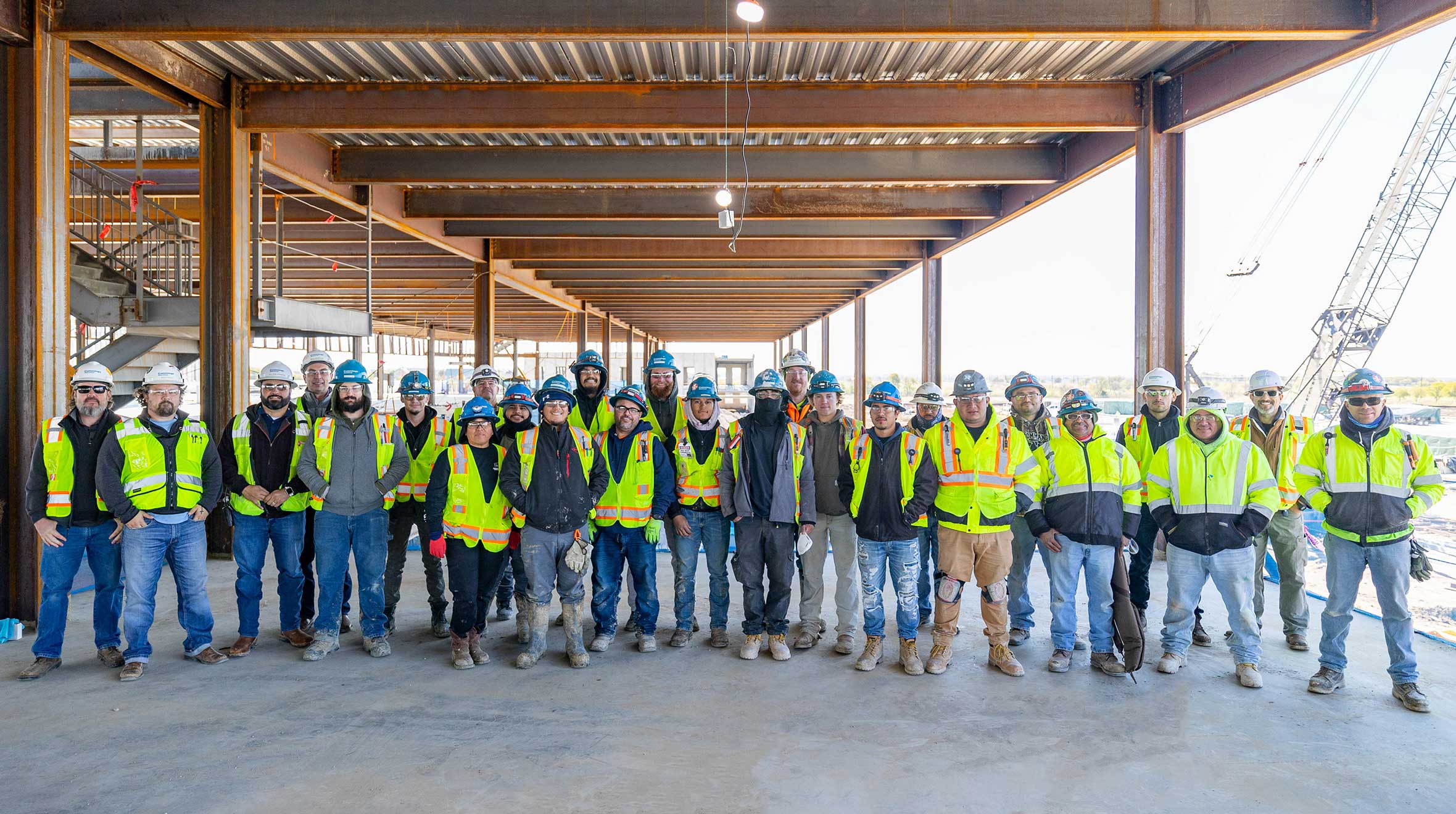 A group of construction workers smiling and posing together for a photo at a construction site