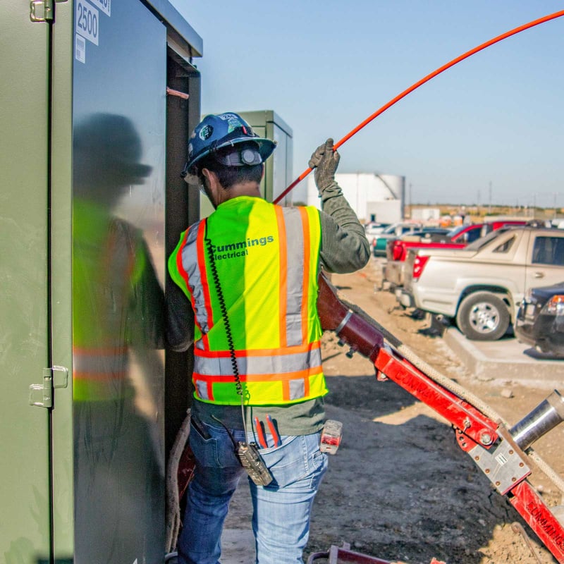 A-man-with-a-hard-hat-and-a-safety-vest-installing-a-cable-1600x1600