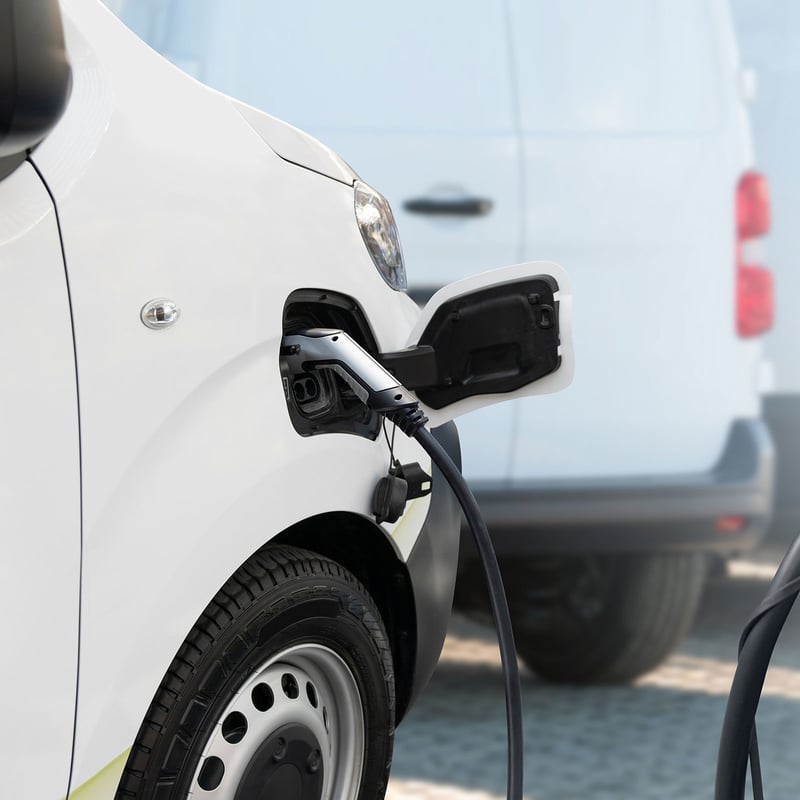 Closeup of an electric delivery van plugged in to an EV charger