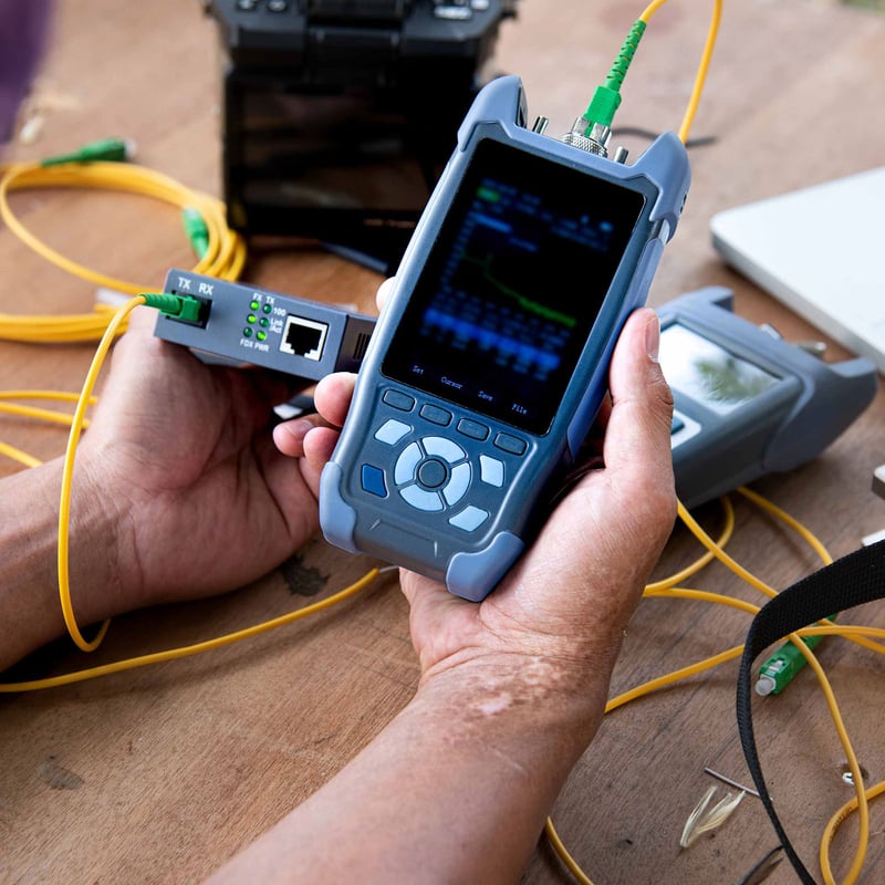 Technician using a fiber optic tester to analyze network connectivity,