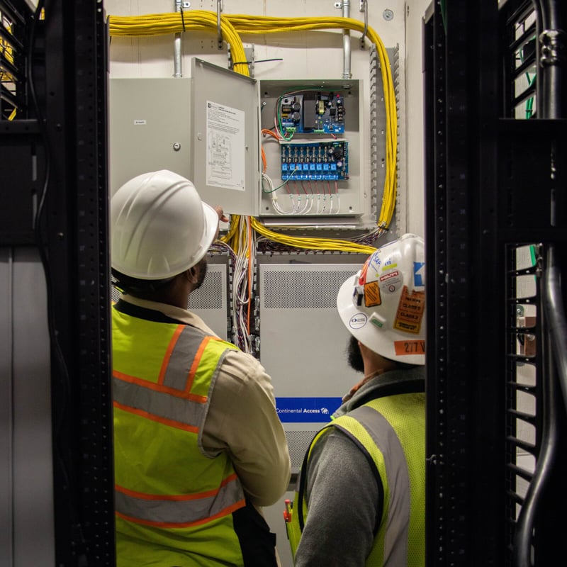 Two men wearing hard hats, engaged in a construction site discussion, showcasing teamwork and safety in their work environment