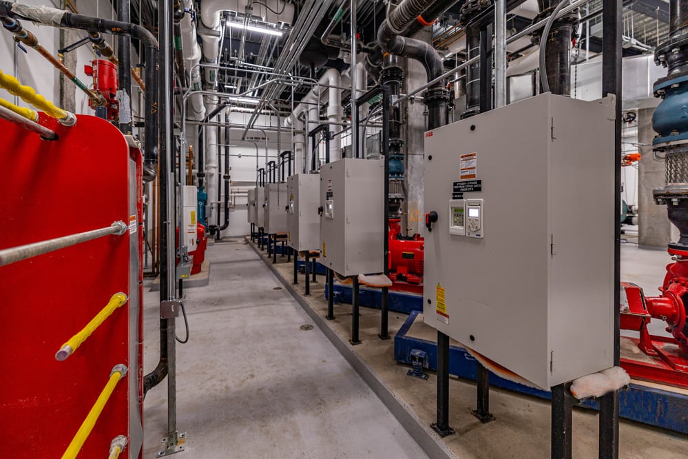 Rows of electrical control panels surrounded by piping and conduit