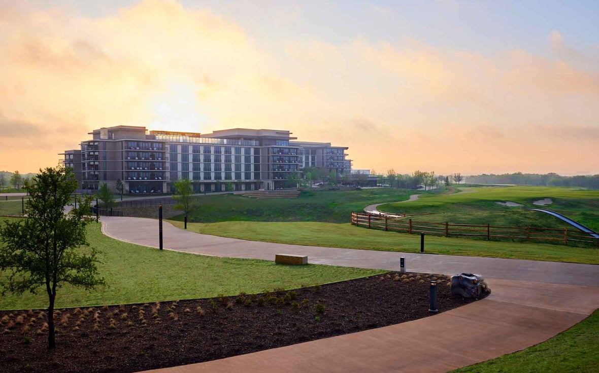 Exterior sunrise view of a resort and spa with golf green grass surrounding 