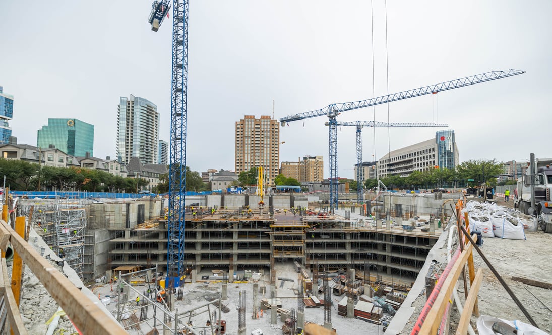 view of an active construction job site surrounded by high-rise buildings and cranes