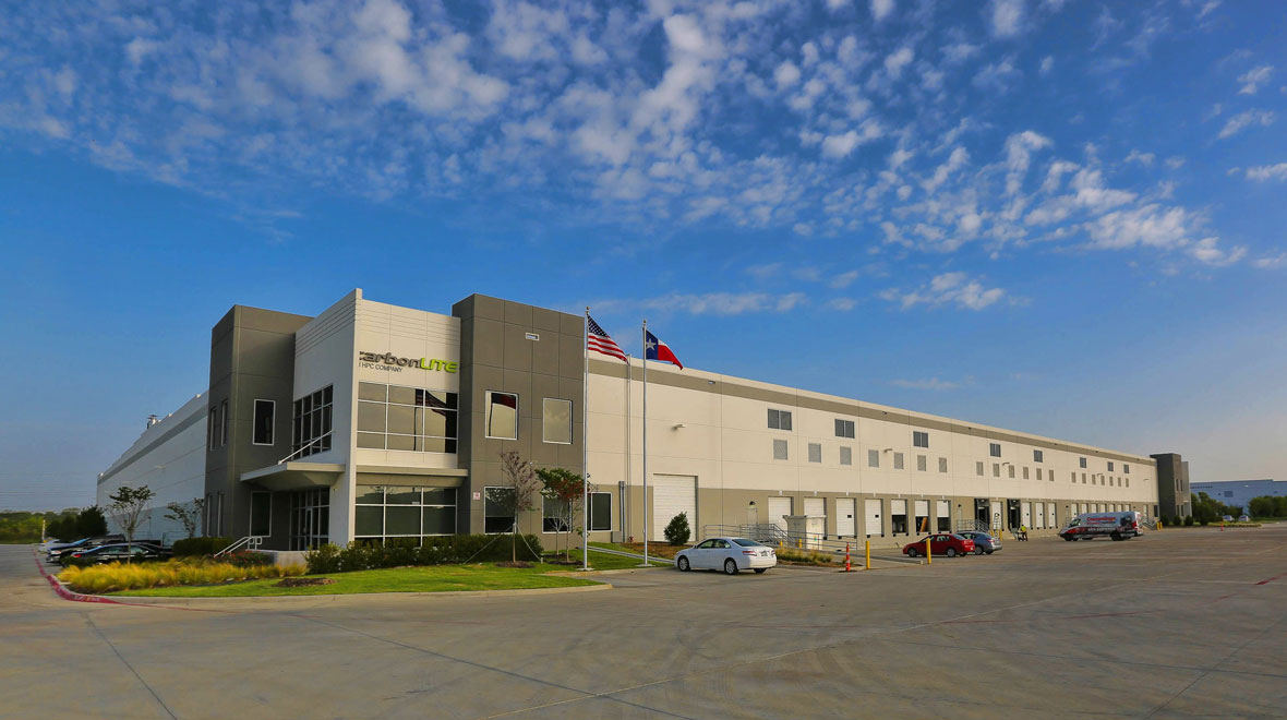 outdoor front view of a manufacturing facility with a few cars parked outside of the building