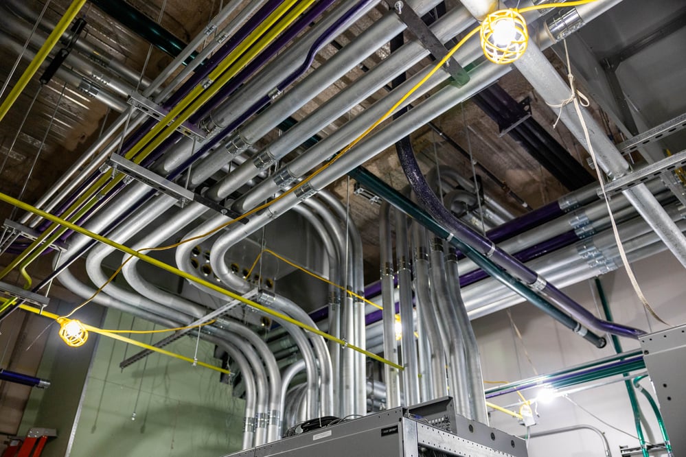 ceiling view of metal and colorful conduit routing into electrical equipment