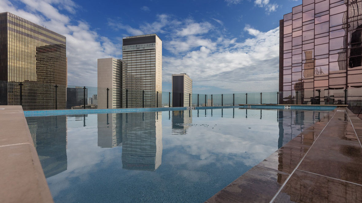 exterior view of a highly reflective pool on a downtown terrace overlooking multiple high-rise buildings