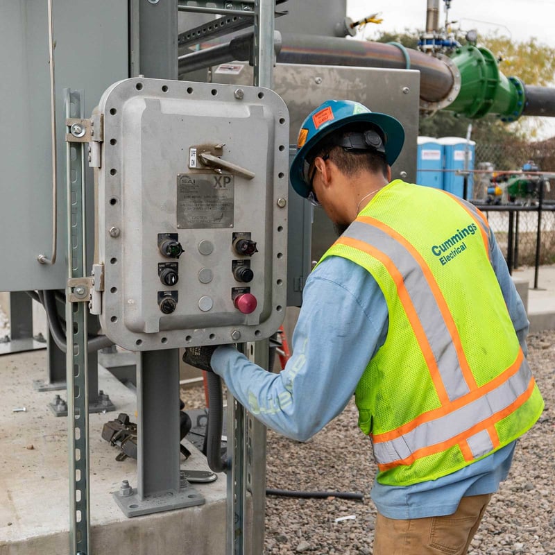 Cummings electrician in full protective equipment working on industrial panel