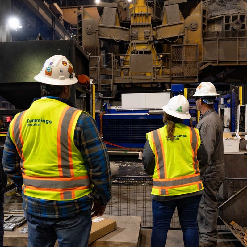 Cummings worker in an industrial facility with hard hats and visibility vests