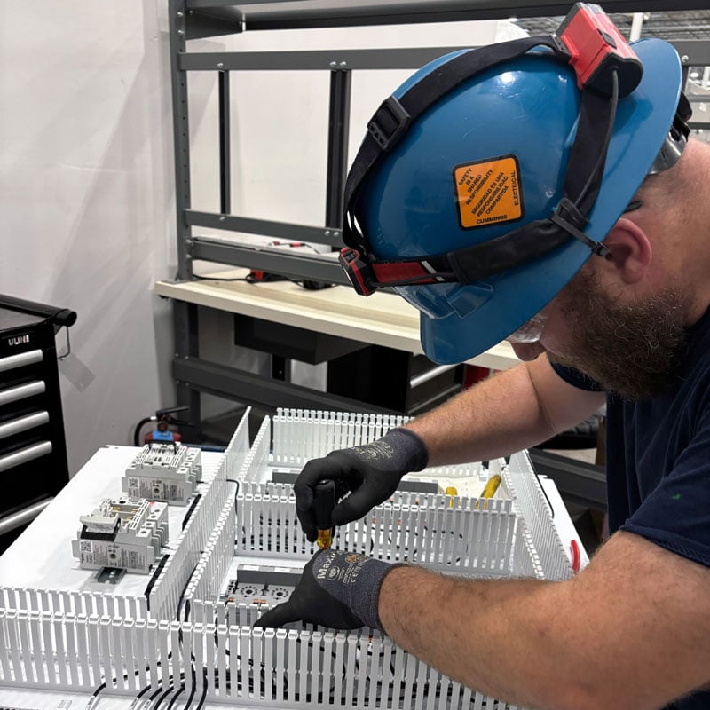 A man with a hard hat working on a modular control board