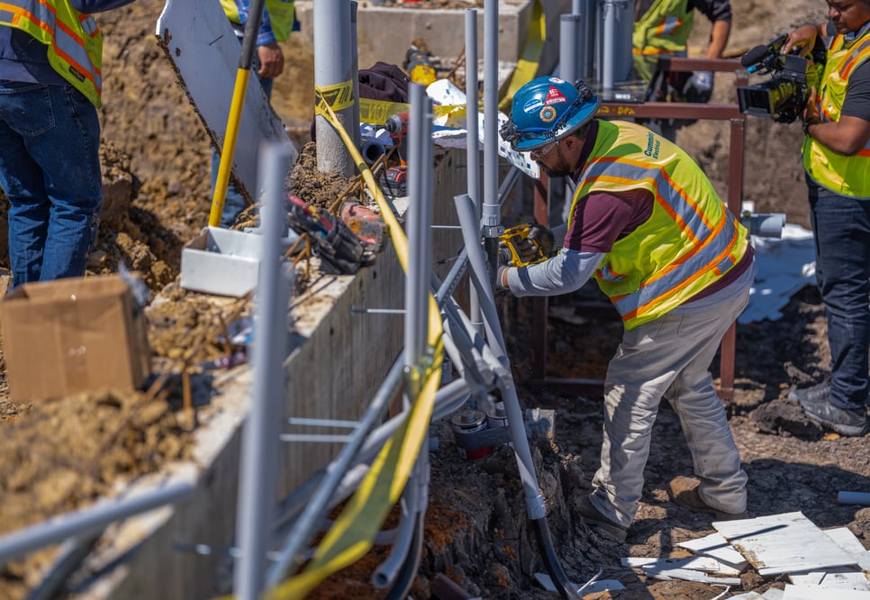 Cummings technician in PPE working in a trench with conduits surrounding