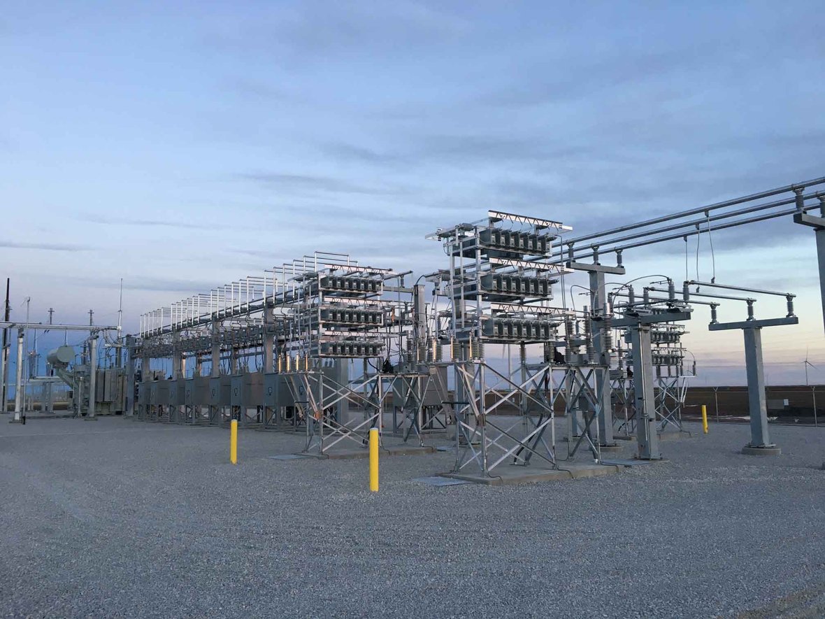 Wide-angle, sunset view of a large utility substation with multiple transformers and switchgear structures