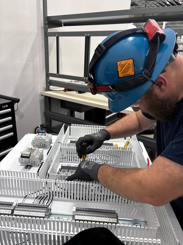 A man with a hard hat working on a modular control board