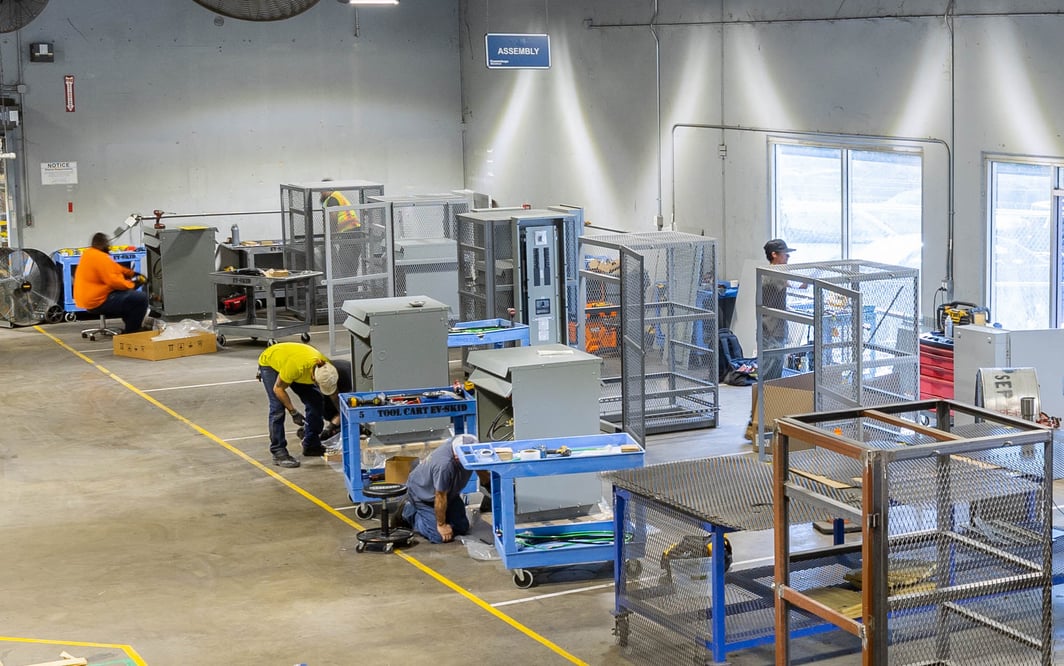 Overhead view of multiple prefabricated electrical skids being produced in a manufacturing facility