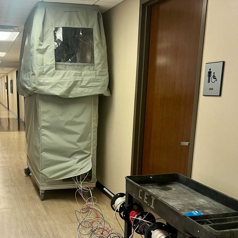 Worker-repairing live electrical systems inside of a protective cover in a building hallway